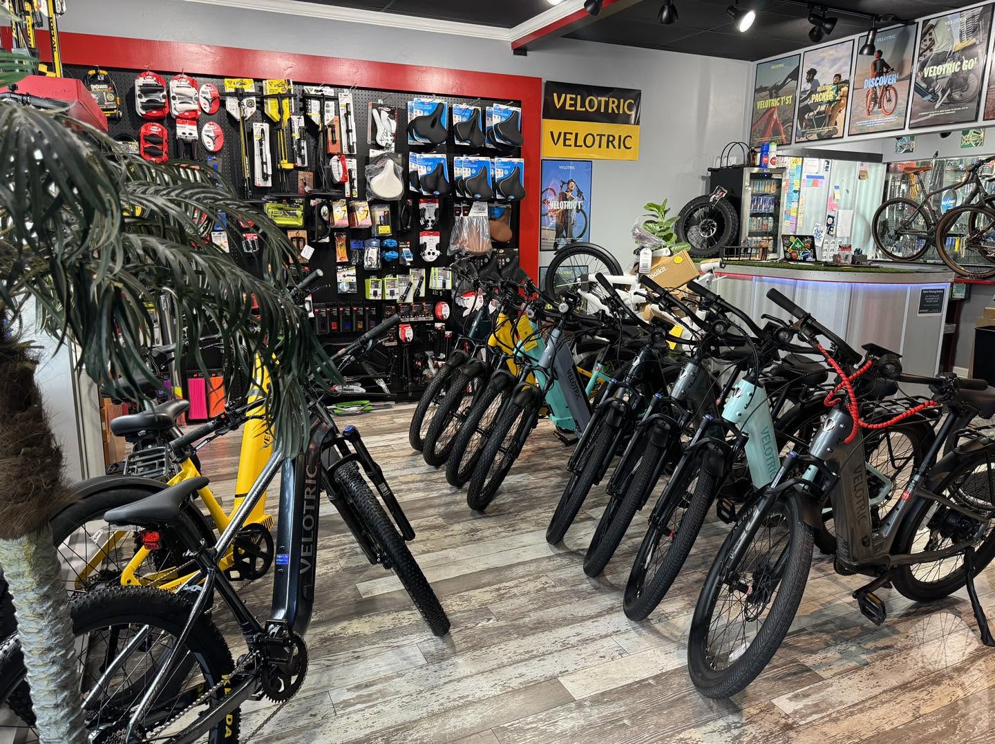 Rows of Velotric E-Bikes lined up on the shop floor beneath a wall of accessories.